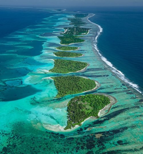 A breathtaking aerial shot of a Maldives atoll with vibrant blue waters and green islands.