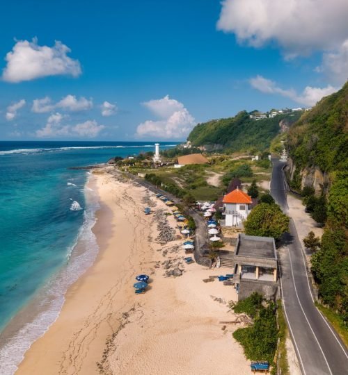 Aerial view of a Bali beach with a lighthouse and scenic coastline in Indonesia.