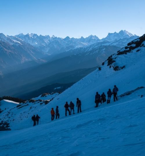 Group of trekkers navigating snowy slopes in the majestic Singtur Range, India.